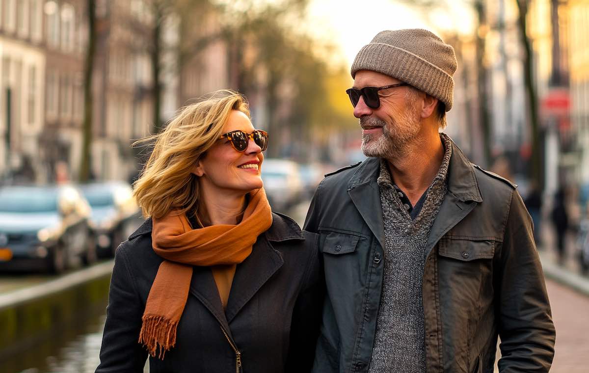 a 50 year blonde woman and man with hat walking through Amsterdam having a date